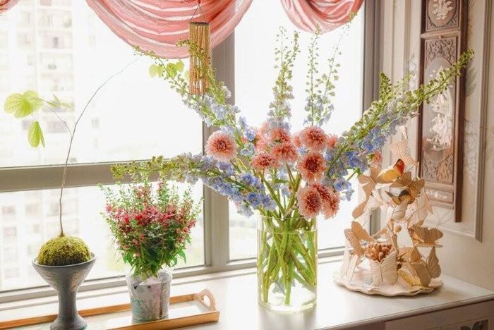 Tác phẩm điêu khắc đàn bướm bằng gỗ đặt cạnh lọ hoa tươi tạo nên sự tương phản thú vị giữa nét tĩnh của mỹ nghệ và sức sống của thiên nhiên. Từng nhành hoa vươn cao phóng khoáng như phản chiếu tâm hồn tự do của chủ nhân ngôi nhà.
