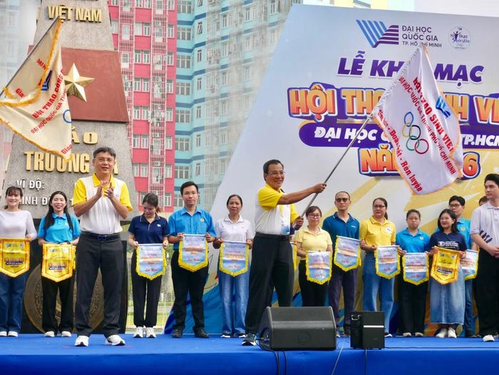 TS Lưu Trung Thủy (người cầm cờ) - Trưởng Ban Công tác sinh viên ĐHQG-HCM được Trưởng Ban Chỉ đạo Hội thao Nguyễn Minh Tâm trao cờ truyền thống.