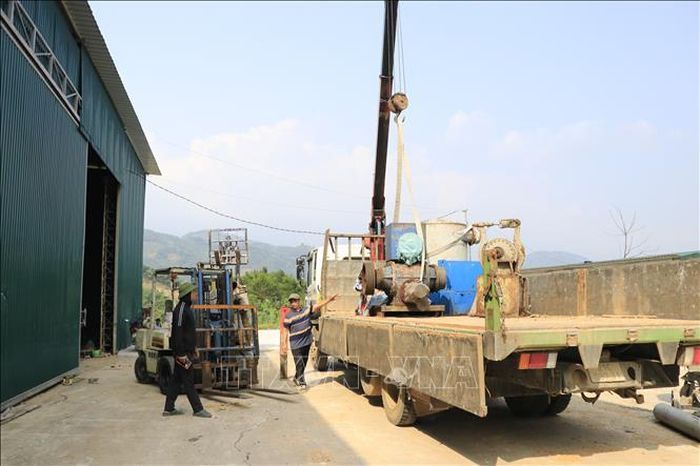 Công nhân tháo dỡ máy móc, trang thiết bị di dời ra khỏi khu vực nhà xưởng tại cơ sở tái chế giấy ở thôn Toàn An, xã Đông Cuông (Lào Cai). Ảnh: Anh Thùy/TTXVN