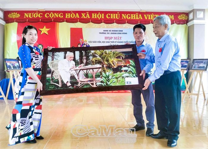 Đồng chí Bùi Công Bửu, nguyên Phó Bí thư Thường trực Tỉnh ủy, nguyên Chủ tịch HĐND tỉnh, nguyên Chủ tịch UBND tỉnh (bìa phải), trao tặng bức ảnh Bác Hồ cho Ban Giám hiệu Trường Tiểu học 1 Khánh Bình Đông.