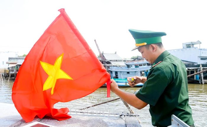 Cán bộ Đồn Biên phòng Cái Đôi Vàm thay cờ Tổ quốc cho tàu cá của ngư dân vươn khơi bám biển.