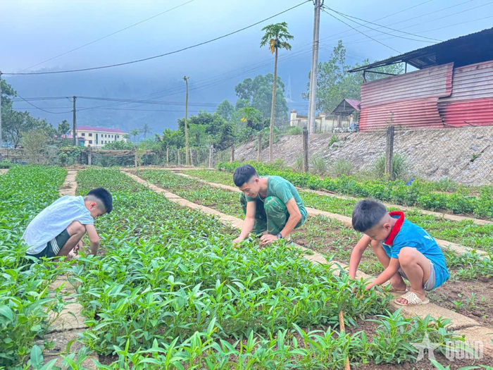 Chiến sĩ Đồn Biên phòng Pa Thơm cùng con nuôi chăm sóc vườn rau. 