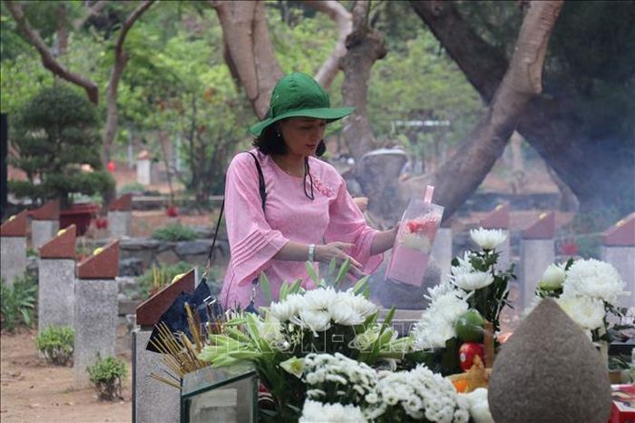 Du khách sử dụng “giỏ lễ xanh” gồm hoa tươi, trái cây, vật phẩm thân thiện môi trường dâng cúng tại Nghĩa trang Hàng Dương, Công Đảo. Ảnh: Thanh Vũ/TTXVN