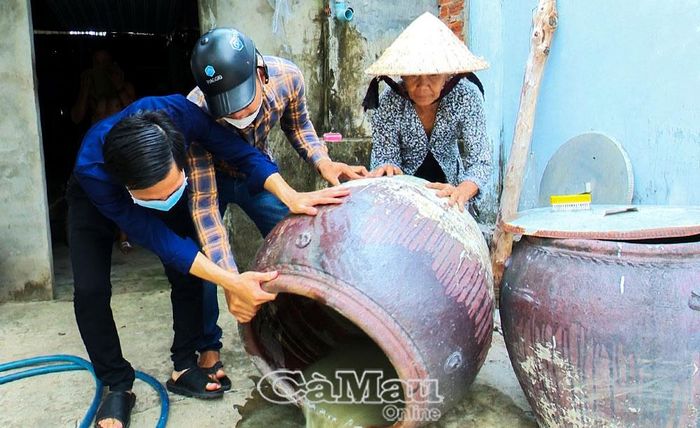 Đoàn viên thanh niên kiểm tra và giúp người dân vệ sinh dụng cụ chứa nước để diệt lăng quăng, phòng bệnh sốt xuất huyết.