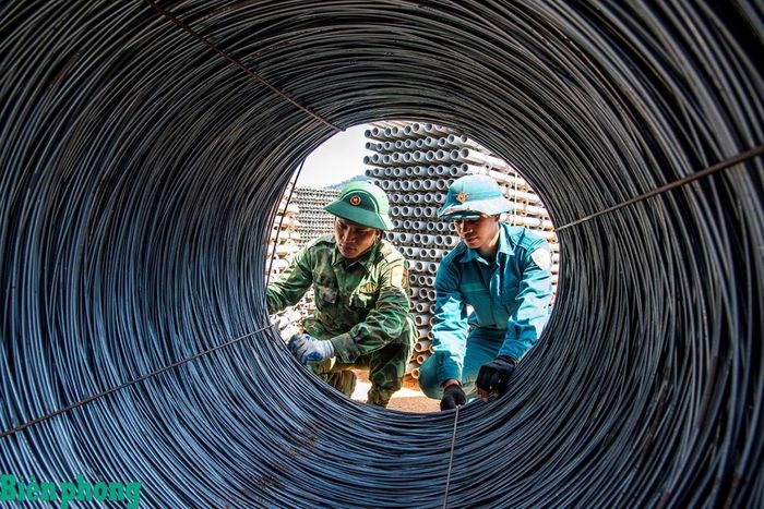 Chiến sĩ dân quân thường trực Hồ Văn Thân và Thượng úy A Lăng Vũ đang tháo đai sắt để đan rọ sắt cột nhà. Ảnh: Lê Văn Chương