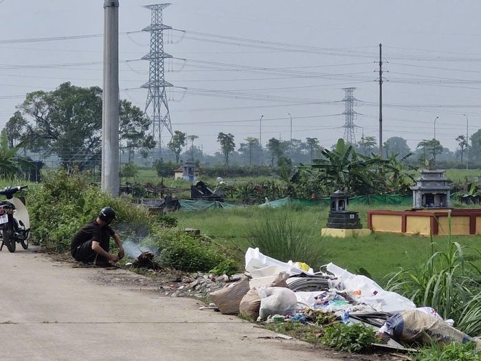 Một người dân ở xã Quốc Oai đốt rác tại một điểm tập kết rác tự phát ven đường. Ảnh: Đức Duy