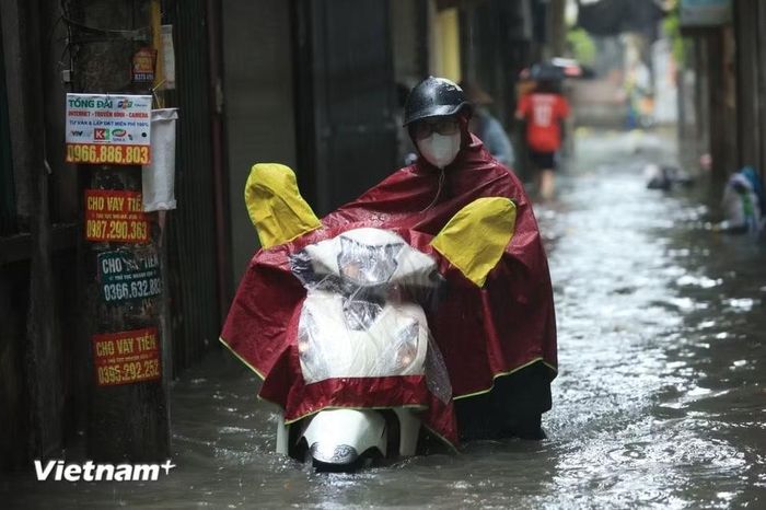 Người dân dắt xe máy qua chỗ ngập sâu do phương tiện chết máy. (Ảnh: Hoài Nam/Vietnam+)