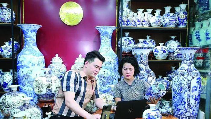 Nghệ nhân Trần Trung Hiếu (Bát Tràng, Hà Nội) cùng đồng nghiệp thảo luận cách đưa sản phẩm làng nghề lên các nền tảng thương mại điện tử.