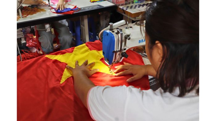 Thợ may Đỗ Thị Minh thực hiện công đoạn ghép sao vàng trên vải cờ đỏ. Ảnh: Cẩm Hà, Thu Trang