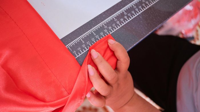 Đo cắt vải may cờ thủ công. Ảnh: Cẩm Hà, Thu Trang