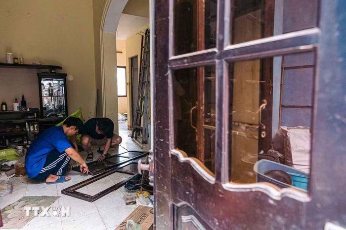 Người dân tranh thủ tháo dỡ cửa và di chuyển đồ đạc khỏi căn nhà nằm trong diện giải phóng mặt bằng. (Ảnh: Phạm Tuấn Anh/TTXVN)