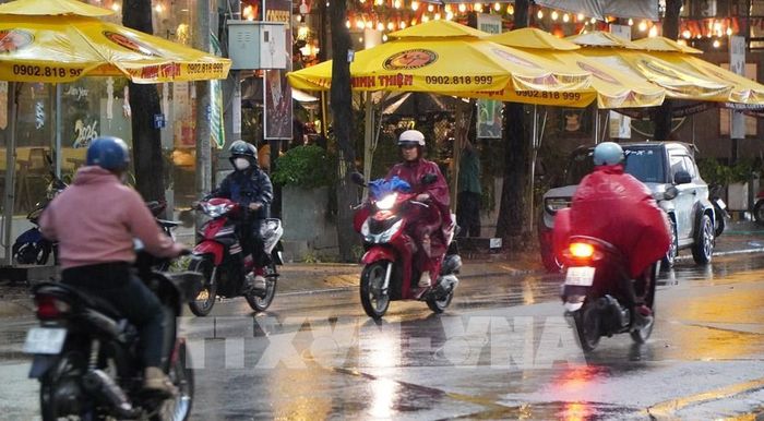 Người dân phường Mỹ Tho tham gia giao thông dưới cơn mưa chiều 15/5. Ảnh: Hồng Thái - TTXVN