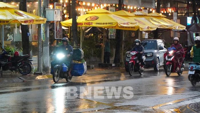 Người dân phường Mỹ Tho tham gia giao thông dưới cơn mưa chiều 15/5. Ảnh: Hồng Thái - TTXVN
