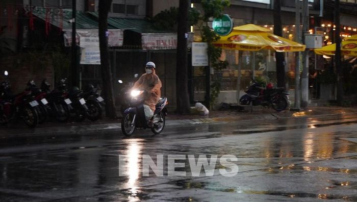 Người dân phường Mỹ Tho tham gia giao thông dưới cơn mưa chiều 15/5. Ảnh: Hồng Thái - TTXVN