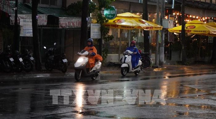 Người dân phường Mỹ Tho tham gia giao thông dưới cơn mưa chiều 15/5. Ảnh: Hồng Thái - TTXVN