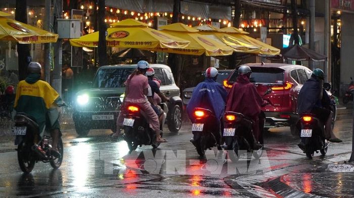 Người dân phường Mỹ Tho tham gia giao thông dưới cơn mưa chiều 15/5. Ảnh: Hồng Thái - TTXVN