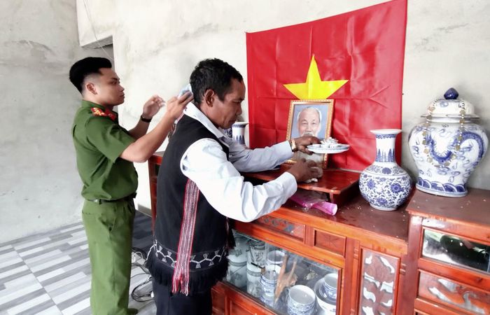 Cán bộ Công an xã biên giới Avương giúp ông Avô A Nhớt lau dọn bàn thờ Bác Hồ.