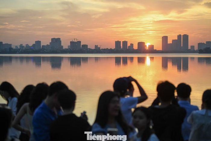 Mọi người tập trung đông tại khu vực ven Hồ Tây trên đường Thanh Niên để ngắm trọn khoảnh khắc mặt trời dần lặn xuống mặt hồ mà không bị che khuất bởi các tòa nhà cao tầng.