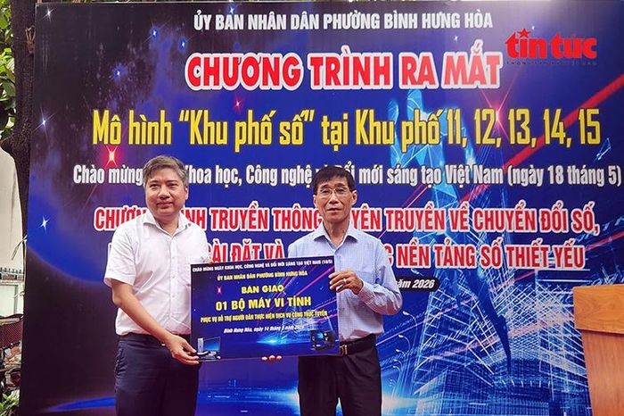 Ông Nguyễn Việt Quế Sơn, Bí thư Đảng ủy phường Bình Hưng Hòa (bên trái) trao bảng tượng trưng tặng một bộ máy vi tính nhằm phục vụ, hỗ trợ người dân thực hiện dịch vụ công trực tuyến.