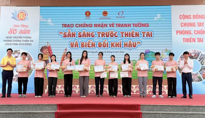 Ông Phạm Đức Luận (áo trắng) Cục trưởng Cục Quản lý đê điều và Phòng, Chống thiên tai trao chứng nhận vẽ tranh tường cho các em học sinh trong khuôn khổ Tuần lễ Quốc gia Phòng, chống thiên tai 2026.