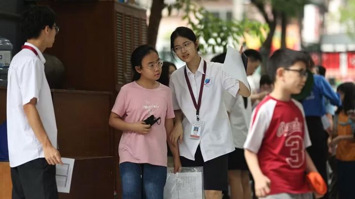 Thí sinh được các tình nguyện viên hỗ trợ tìm phòng thi. (Ảnh: ĐẠI THẮNG)