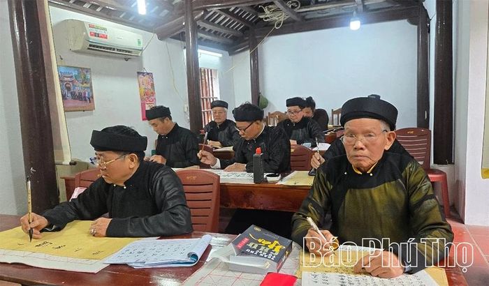 Ông Vũ Văn Mắm (bên phải) luyện chữ trong giờ học.