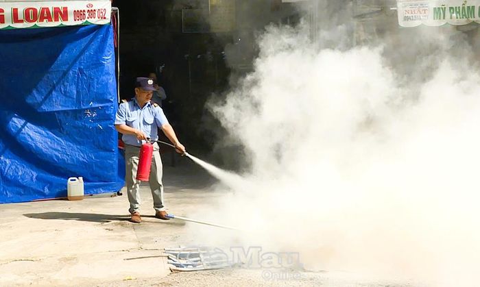 Bảo vệ Công ty Cổ phần ô tô Bảo Toàn tại chợ Ngan Dừa dùng bình chữa cháy xách tay chữa cháy ban đầu.