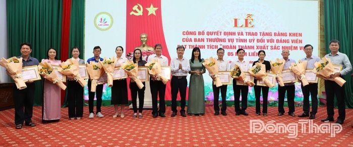 Đồng chí Phạm Văn Chuẩn và đồng chí Trần Thùy Trang, Phó Bí thư Thường trực Đảng ủy phường Cao Lãnh (thứ 7 từ phải sang) trao Huy hiệu Đảng cho các đảng viên.