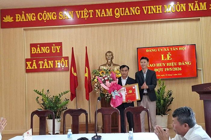 Đồng chí Hồ Quốc Trung, Bí thư Đảng ủy, Chủ tịch HĐND xã Tân Hội trao Huy hiệu Đảng cho đồng chí Hoàng Doãn Hiền