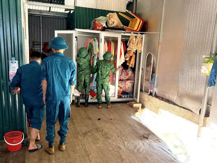 Lực lượng chức năng hỗ trợ người dân di chuyển tài sản, khắc phục hậu quả sau mưa lũ tại xã Lý Quốc.