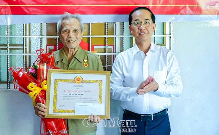 Đồng chí Hồ Thanh Thủy, Phó Bí thư Tỉnh ủy, Chủ tịch Ủy ban MTTQ Việt Nam tỉnh Cà Mau, trao Huy hiệu 65 năm tuổi Đảng cho đảng viên Trần Văn Nhan.