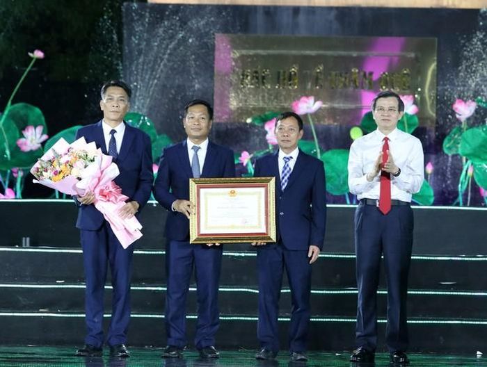 Ông Đoàn Minh Huấn, Ủy viên Bộ Chính trị, Giám đốc Học viện Chính trị Quốc gia Hồ Chí Minh, trao Huân chương Lao động hạng Nhất và tặng hoa cho tập thể lãnh đạo Khu Di tích Quốc gia đặc biệt Kim Liên