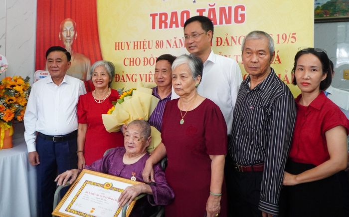 Đồng chí Trần Cẩm Tú và đồng chí Lê Ngọc Quang chụp hình lưu niệm cùng người thân đảng viên Nguyễn Thị Khá. Ảnh: VINH ANH