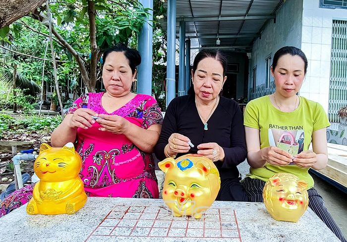Chị Quách Thúy Trọn cùng các thành viên mô hình “Nuôi heo đất mua heo thịt” tham gia bỏ tiền tiết kiệm vào heo đất gây quỹ hỗ trợ hội viên phụ nữ phát triển kinh tế.