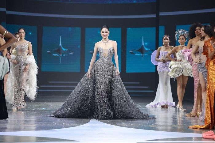 Khoảnh khắc xuất hiện với đầm dạ hội đính kết dày đặc giúp Hương Giang trở thành tâm điểm sân khấu. Thiết kế corset ôm sát phần thân trên kết hợp chân váy xòe lớn tạo hình ảnh như “nữ hoàng ngân hà”. Kiểu tóc vuốt gọn cùng lọn tóc uốn trước trán giúp tổng thể mang hơi thở điện ảnh cổ điển.