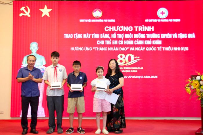 Chủ tịch Hội Chữ thập đỏ thành phố Hà Nội Lê Tự Lực trao tặng máy tính bảng hỗ trợ việc học tập cho 3 em học sinh phường Phú Thượng. Ảnh: PV
