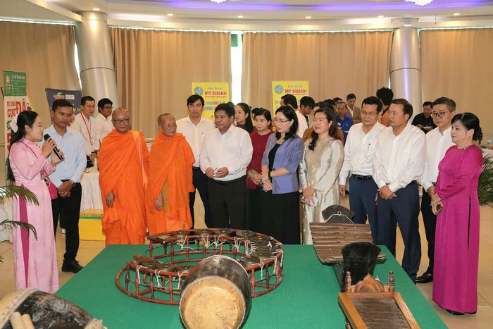 Thứ trưởng Bộ Dân tộc và Tôn giáo Y Thông (áo trắng đứng cạnh nhà sư) và các đại biểu tham quan khu trưng bày nhạc cụ của đồng bào dân tộc Khmer.