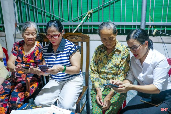Bà Nguyễn Thị Liễu (người áo sọc xanh) - Chi hội trưởng Chi hội Phụ nữ thôn 16 (xã Cẩm Xuyên) hướng dẫn người dân thực hiện việc cài đặt và sử dụng i-HaTinh.