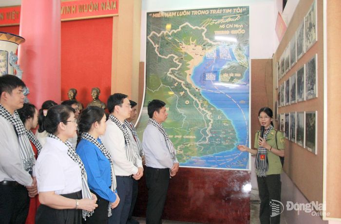 Các đại biểu nghe thuyết minh tại Đền tưởng niệm Di tích căn cứ Trung ương cục miền Nam. Ảnh: Nga Sơn