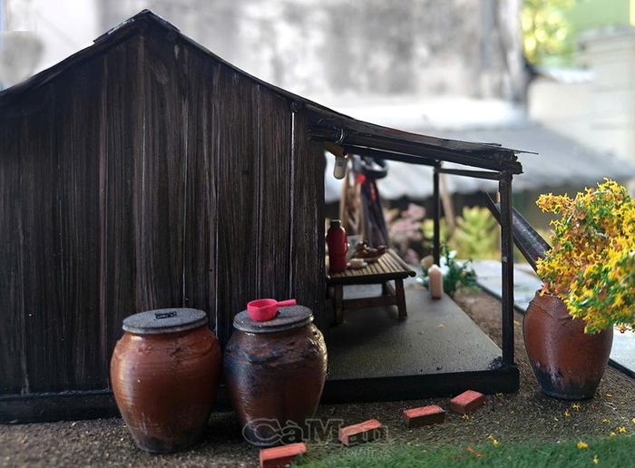 Đôi lu nước mưa nép mình bên vách đất cùng chiếc chõng tre bình yên dưới hiên nhà - nơi lưu giữ những buổi chiều trà muộn của ông bà.