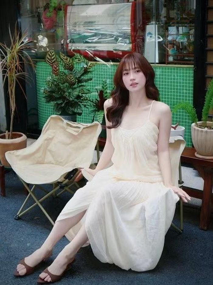 Trong bộ ảnh chụp tại quán cà phê, Phương Anh Đào lựa chọn váy hai dây màu kem với chất liệu mềm mại. Thiết kế đơn giản giúp nữ diễn viên tôn vóc dáng thanh mảnh và bờ vai gợi cảm nhưng vẫn giữ được nét tinh khôi, nền nã. Mái tóc uốn nhẹ cùng lối trang điểm trong trẻo càng làm nổi bật vẻ đẹp dịu dàng của cô.