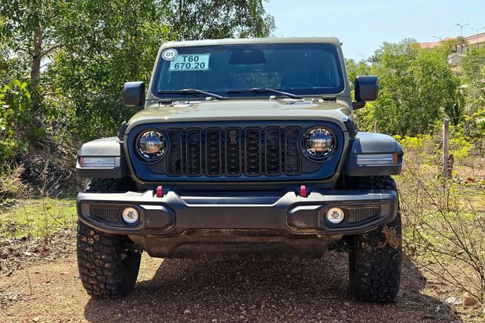  Mẫu SUV địa hình của Jeep vẫn giữ nguyên những chi tiết thiết kế đã trở thành biểu tượng. Cụm đèn LED dạng tròn bao gồm đèn chiếu sáng ban ngày và cụm đèn pha với chức năng tự động điều chỉnh pha/cos. Lưới tản nhiệt 7 khe có viền nổi khối tối màu. Nắp ca-pô ở bản Rubicon có 2 khe thoát gió thể thao cùng logo Rubicon 2 bên, kết hợp các móc kéo sơn đỏ ở cản trước và sau. 