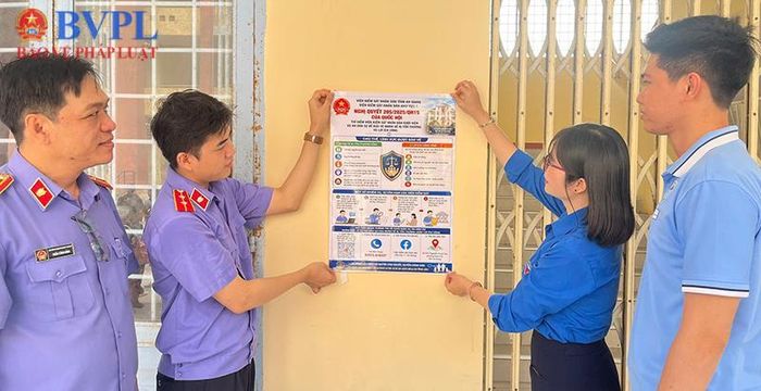  Đại diện VKSND khu vực 1 - An Giang và Bí thư Đoàn Trường Trung cấp An Giang 1 dán áp-phích tuyên truyền tại bảng tin của nhà trường.