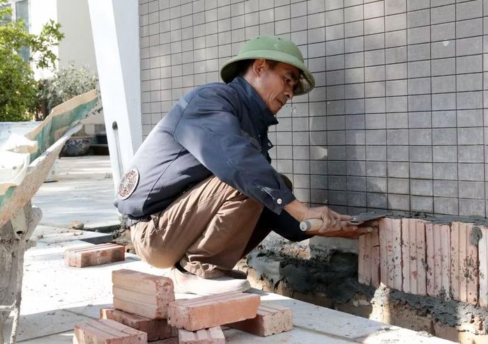 Để chống chọi cái nóng ngoài trời, nhiều lao động tự do đã tự trang bị áo gắn quạt làm mát. (Ảnh: Tạ Toàn/TTXVN)