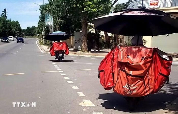 Để chống chọi với nắng nóng, nhân viên chuyển phát nhanh sử dụng ô che cỡ lớn khi lưu thông trên đường phố tỉnh Phú Thọ. (Ảnh: Hoàng Hùng/TTXVN)