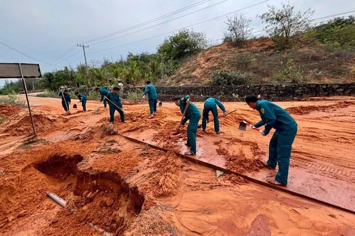 Lực lượng chức năng xã Phan Rí Cửa đang khẩn trương khắc phục điểm sạt lở, san gạt đất cát tràn xuống mặt đường.
