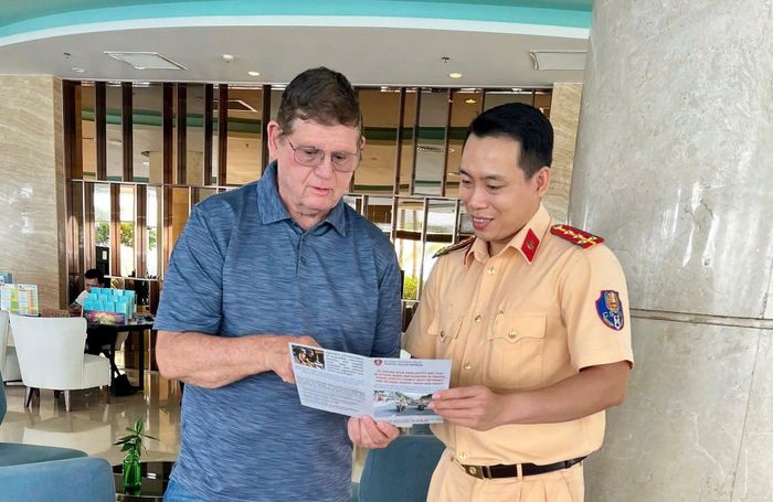 Cảnh sát giao thông phát tờ rơi tuyên truyền song ngữ Anh - Việt cho du khách nước ngoài đang du lịch, nghỉ dưỡng tại Đặc khu Phú Quốc.