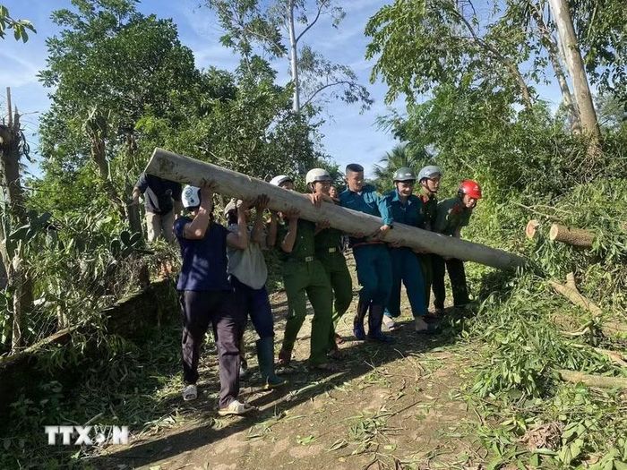 Lực lượng Công an tỉnh Gia Lai giúp người dân dọn dẹp trụ điện ngã đổ gây cản trở giao thông. (Ảnh: Sỹ Thắng/TTXVN)