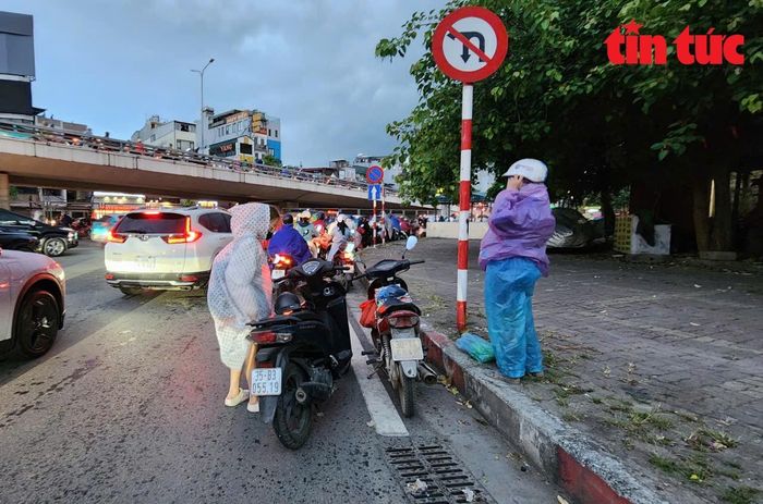 Người điều khiển phương tiện giao thông dừng xe mặc áo mưa trên đường Láng.
