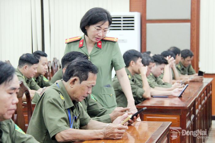 Cán bộ công an phường hướng dẫn thí sinh cách thức, thủ tục trước khi thi trực tuyến trên thiết bị điện thoại. Ảnh: Trần Danh